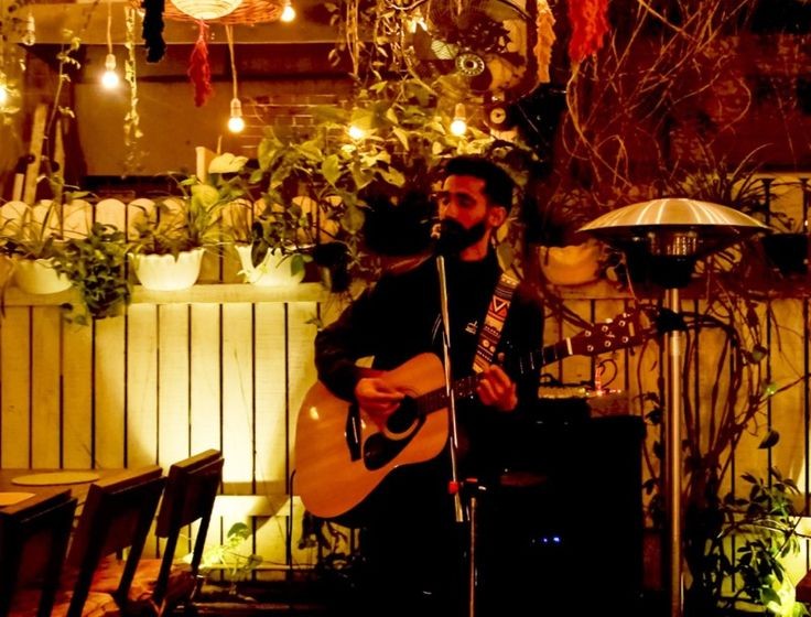 Live music performance at Brewnest Cafe with guitarist under warm lights and cozy ambiance, cafe with live music